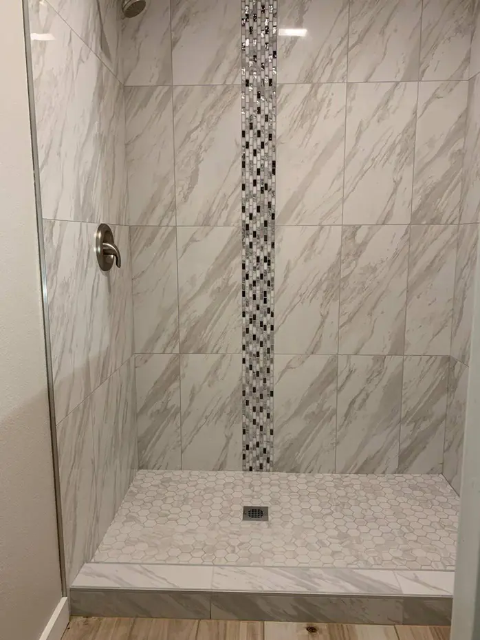 Bathroom renovation with marble vanity and pebble accent wall
