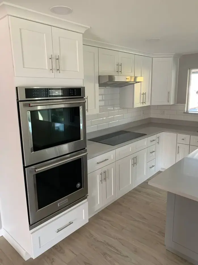 White kitchen cabinets with double oven and subway tile backsplash